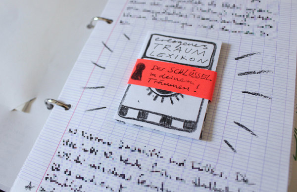 ein winziges Zine mit Hilfe eines Papierstreifens auf einem Blatt Papier befestigt