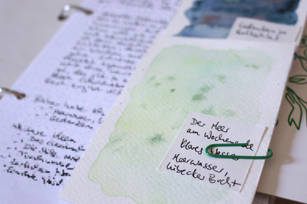 mehrere Zettel verschiedener Größe mit einer Büroklammer an ein beschriebenes Blatt Papier geklammert